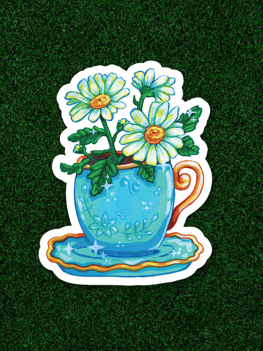 Sticker of a blue teacup with flowers on a grass background