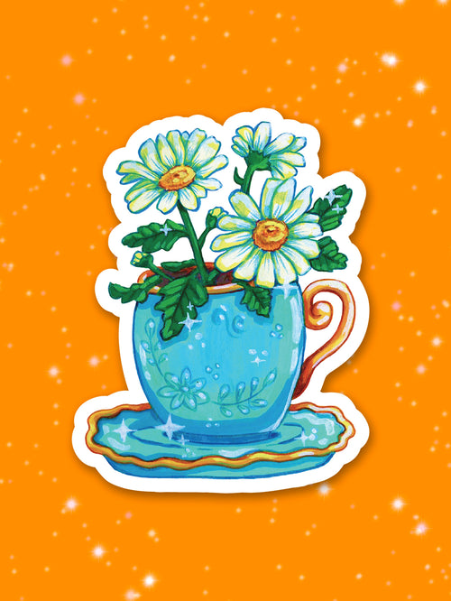 Blue teacup with gold handle with white flowers in it on an orange background